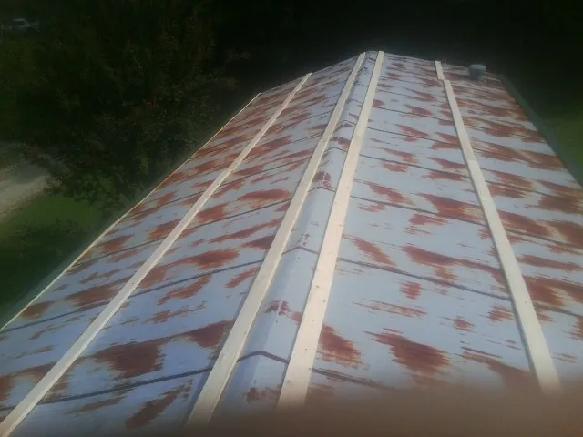 Rusted metal roof panels with new wood purlins before replacement — Storm Damage Roof Repair in Oakland Mills by Roofing Brothers
