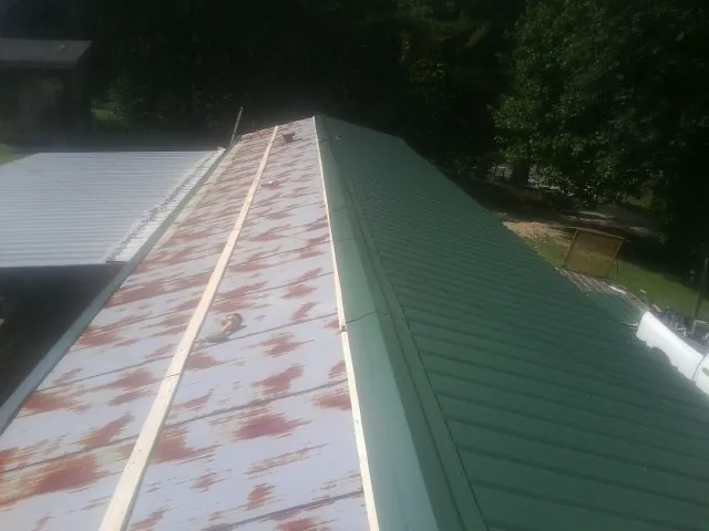 Old rusted panels beside newly installed green metal roofing — Wind Damage Roof Repair by Roofing Brothers in Oakland Mills