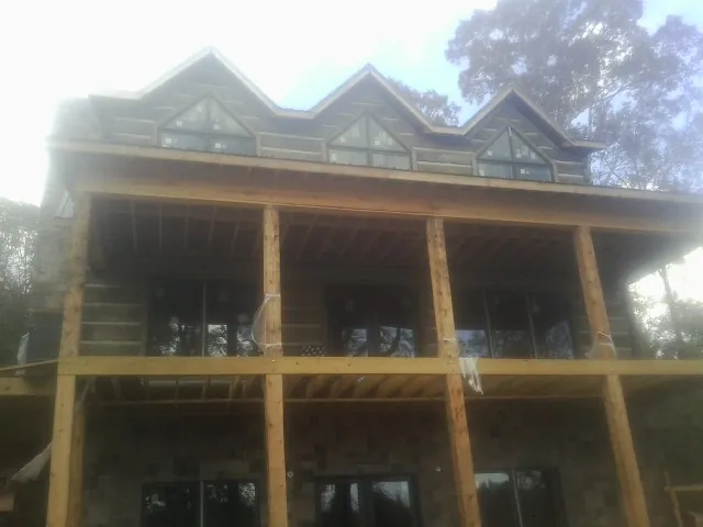 Dormers and porch framing on a large log home under construction — Roof Coating work by our crew in Oakland Mills