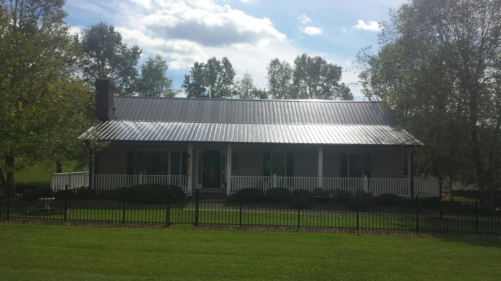 Gray metal roof on a brick ranch with a full width front porch — Gutter Guard Installation work by our crew in Oakland Mills