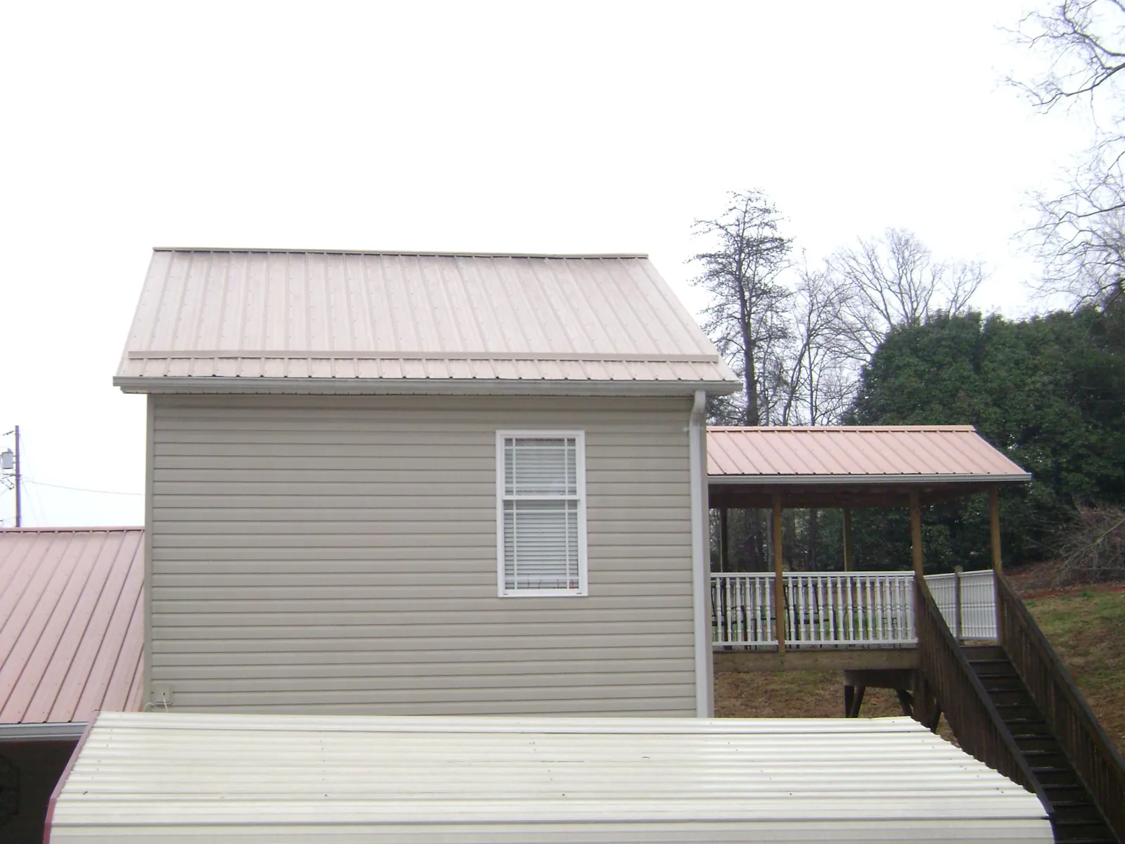 Tan metal roofs on a two story addition and attached porch, from a Roof Replacement job in Oakland Mills