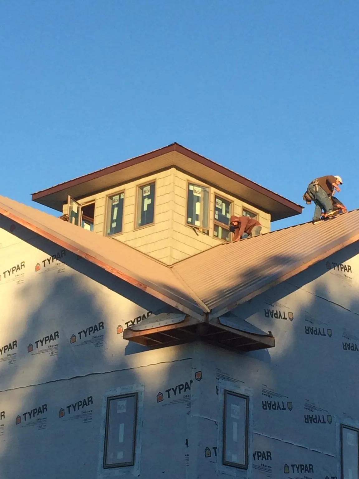 Roofers working around a rooftop cupola on a new metal roof at sunset — Roof Waterproofing in Oakland Mills by Roofing Brothers